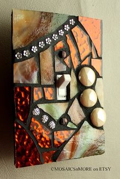 a decorative light switch plate with an orange and brown mosaic design on it's side