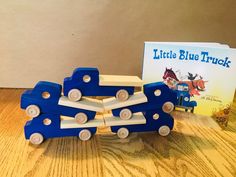 a wooden toy truck next to a little blue truck book on a table with an open book