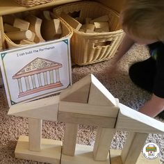 a young child playing with wooden blocks in front of a sign that says i can build the house