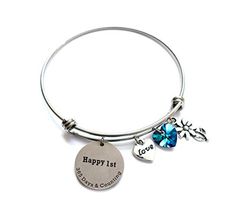 a silver bang bracelet with charms and a happy 1st birthday charm