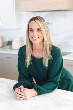 a woman sitting at a kitchen counter smiling