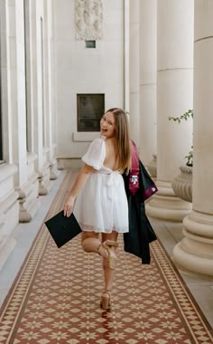 a woman in a white dress is walking down the hall with her hand on her hip