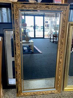 a large gold framed mirror sitting on top of a table