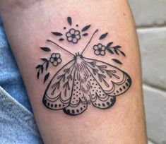 a small black and white butterfly tattoo on the right arm, with flowers around it