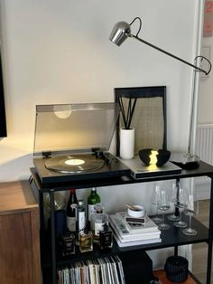 a record player sitting on top of a table next to a shelf with records and drinks