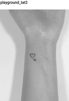 a small heart tattoo on the wrist with a bird flying by it's side