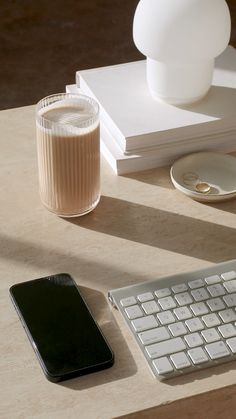 a computer keyboard sitting on top of a wooden desk next to a cup of coffee