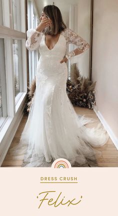 a woman standing in front of a window wearing a white dress