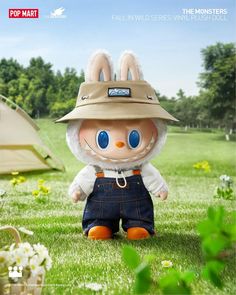 a stuffed animal wearing overalls and a hat in the grass with a tent behind it