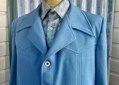 Show off your inimitable style with this amazing 1970's vintage men's blazer! Crafted from a textured polyester, its sky blue colour and other unique details make it stand out in the crowd. It features an exaggerated notched collar, Western-style peaked yokes, and panelling front and back. It has marbled buttons, two slanted welt pockets and short side splits. Plus, it's lined with a stylish, groovy paisley fabric - talk about a far out fashion statement! Size XXLarge Measurements: Chest: 122 cm / 48 inches Shoulder: 48 cm / 19 inches Length: 76 cm / 30 inches Sleeve: 66 cm / 26 inches 100% Polyester This item is one of a kind. BUYING VINTAGE:                                                                                                                                           While all Blue Fitted Collared Blazer, Fitted Blue Collared Blazer, Blue Retro Long Sleeve Blazer, Blue Long Sleeve Retro Blazer, Vintage Blue Single Breasted Outerwear, Vintage Blue Single-breasted Outerwear, Retro Blue Outerwear With Buttons, Retro Fitted Blue Outerwear, Fitted Retro Blue Outerwear