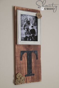 a wooden frame with the letter t on it and two pictures hanging from the wall