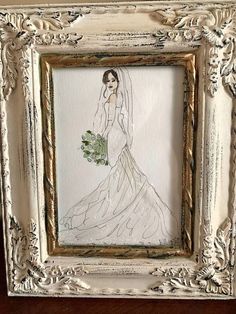 a drawing of a bride in a white dress holding a bouquet of flowers is framed in an ornate gold frame