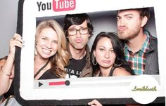 a group of people holding up a photo booth with the words you tube on it