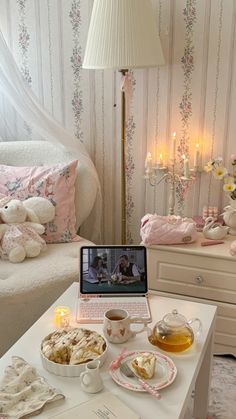 a laptop computer sitting on top of a white table next to a cup of tea