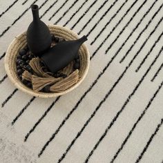 two black vases sitting on top of a white and black striped table cloth next to each other