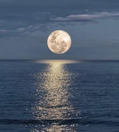 the full moon is reflected in the water as it rises above the ocean's horizon