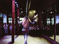 a woman with long blonde hair walking down the runway in front of a group of people