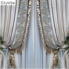 curtains with tassels hanging from them in front of a window, next to plants