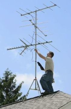 a man standing on top of a roof next to a tv antenna