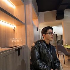 a man sitting in front of a wine glass rack with glasses on it's shelves