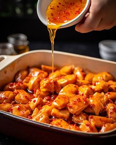 someone pouring sauce on some food in a pan