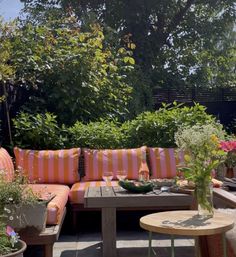 an outdoor seating area with potted plants and flowers on the table in front of it