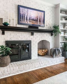 a living room with white brick fireplace and wood burning logs in front of the fire place