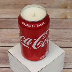 a coca - cola can sitting on top of a box with a candle in it