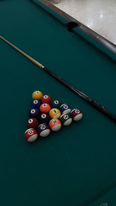 billiards and pool balls are arranged on the green table in front of a pool cue