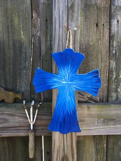 a blue paper cross sitting on top of a wooden fence