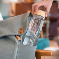 a person holding a gray bag with a bottle in it and a wooden stick sticking out of it