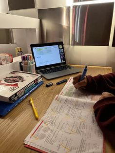 a person sitting at a desk with a laptop and papers in front of them on top of a wooden table