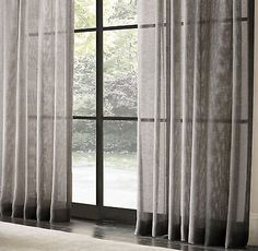 an open window with sheer curtains in front of it and a white rug on the floor