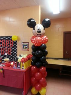 a mickey mouse balloon column in the middle of a room with other balloons and decorations