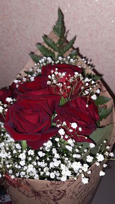 a bouquet of red roses and baby's breath in a brown paper wrapper