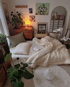 an unmade bed sitting in a bedroom next to a lamp and potted plant