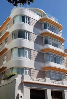 an apartment building with balconies and windows on the top floor is shown in front of a tree