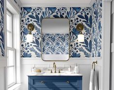 a blue and white bathroom with an ornate wallpaper pattern on the walls, two sinks and a large mirror