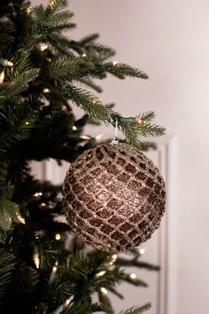 an ornament hanging from the top of a christmas tree in front of a door