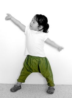 a little boy standing in front of a white wall with his arms out and hands outstretched