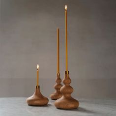 three wooden candlesticks sitting on top of a white table next to each other