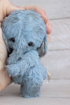 a small blue teddy bear in someone's hand