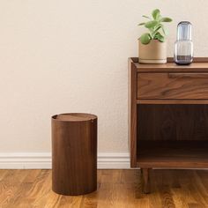 a wooden table with a plant on it next to a brown cabinet and white wall