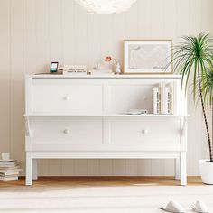 a living room with a white dresser and potted plant on the floor next to it