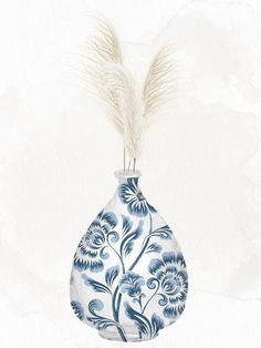 a blue and white floral vase with feathers sticking out of it's top handle