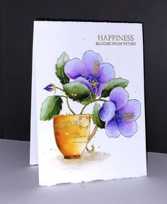 a greeting card with purple flowers in a gold vase