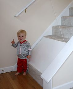 a little boy standing in front of some stairs giving the thumbs up sign with his hand