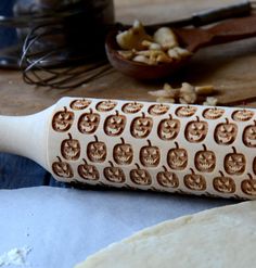 a wooden rolling pin with carved apples on it next to some other baking utensils