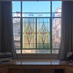 a desk with a computer on top of it in front of a large stained glass window