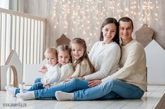 a family sitting on the floor in front of christmas lights